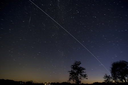 The ISS crossing by over the eveningsky just after dawn in the Netherlands. Left a reflection of the sun on a passing satellite. 4 minutes exposure.のeditorial素材