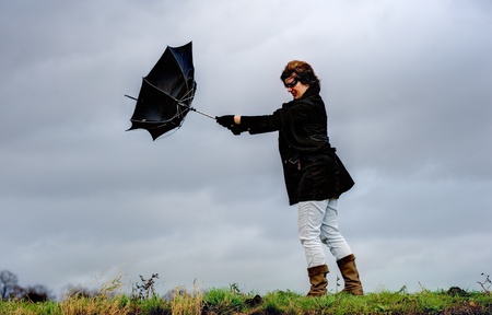 A young woman is fighting against the storm with her umbrellaの写真素材
