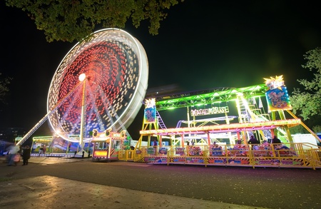 A ferris wheel and a little rollercoaster in the evening at an amusement parkのeditorial素材