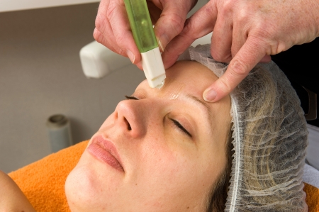A woman s hair between her eyebrows is being waxed の写真素材