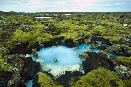 The blue water between the lava stones covered with moss just outside the Blue Lagoon resort of...