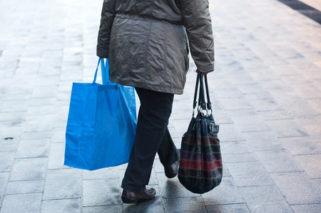 Elderly woman with shopping bag walking on the streetの写真素材