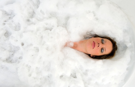 A woman is enjoying a hot bath with her eyes cloes