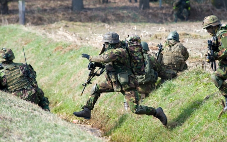 GEESTEREN, NETHERLANDS - MARCH 25  A camouflaged soldier is jumping over a ditch during a training of special forces of the Dutch army on a cold day, March 25, 2013 in the Netherlands のeditorial素材