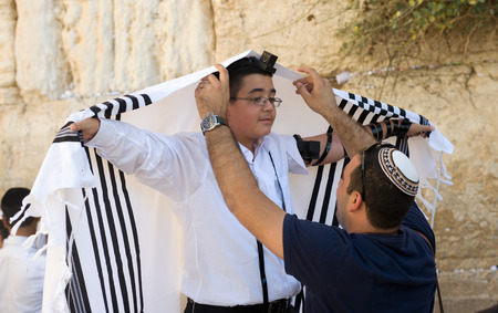 JERUSALEM, ISRAEL - OCT 06, 2014: A jewish man is preparing the tallith of a 13 years old boy before...