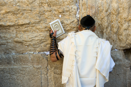 JERUSALEM, ISRAEL - OCT 06, 2014: A jewish man with the torah in his hand is praying against the western wall in the old city of Jerusalemのeditorial素材