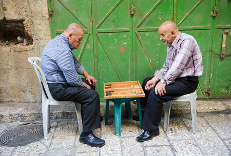 JERUSALEM, ISRAEL - OCTOBER 07, 2014: Two elderly men are playing backgammon in one of the small streets in the old city of Jerusalemのeditorial素材