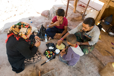 PETRA,  JORDAN - OCT 12, 2014: A family who sells tourists souvenirs in Petra in Jordan is sitting on the ground while they eatのeditorial素材