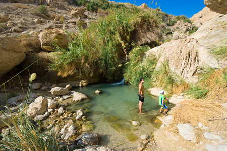 EIN GEDI, ISRAEL - OCT 15, 2014: A man and a child are relaxing in the water of the oasis Ein Gedi close to the dead sea in Israelのeditorial素材