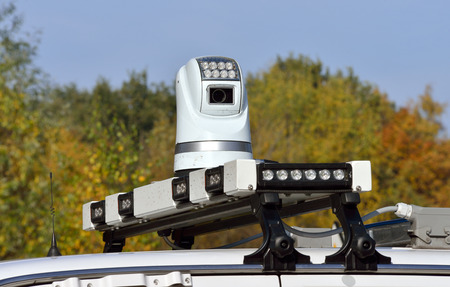 A video camera on the roof of a police car is watching and filming rioting people during a...