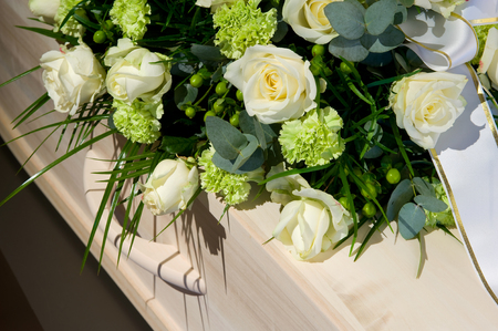 A coffin with a flower arrangement in a morgueの販売画像