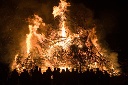 People are watching a huge bonfire, a tradition with easter in Nort-West Europe.の写真素材