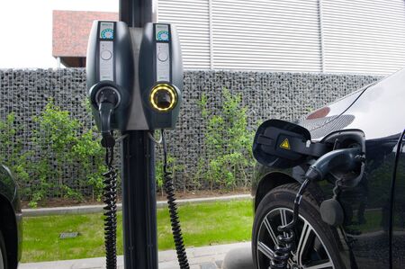 HENGELO, THE NETHERLANDS - MAY 17, 2016: An electric car is parked at a parking spot and is being recharged at a power station.のeditorial素材