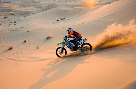 ABU DHABI, UNITED ARAB EMIRATES - JAN 01, 2018: A man on a dirt bike is riding on the hills in the...
