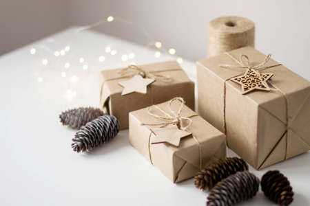Christmas gift wrapping on white background. Decor fir cones, wooden stars, jute rope.