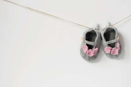 One pair of booties for the baby hanging on a rope. Baby booties for a little girl gray with pink...