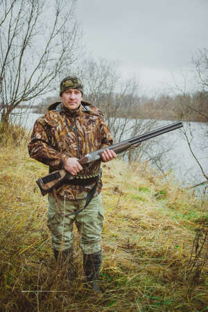 Russia, Kholmogory-October 17 2019 Hunter in camouflage holding a double-barreled gun and looks into...