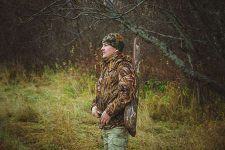Hunter in camouflage clothing with a gun in a case in profile. Autumn hunting for wild ducks.の写真素材