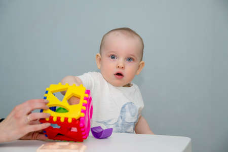 A small child plays at the white table in the sorter.