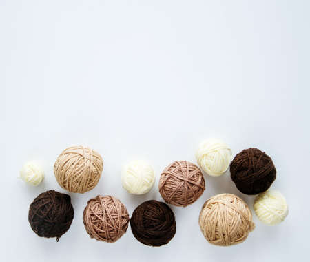 Balls of brown for knitting on a white background are located on the bottom edge of the frame.
