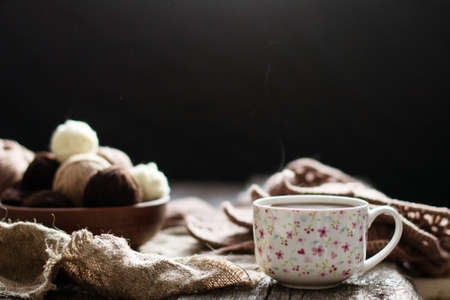 Cup of tea, coffee on an old wooden table against the background of knitting tools.の写真素材