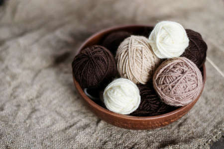 Rustic style - brown wool yarn for knitting in a round vase. Old crumpled cloth.