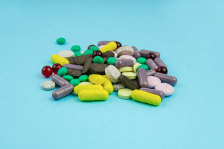 Multi-colored pills and vitamins are a bunch on a blue background.の写真素材