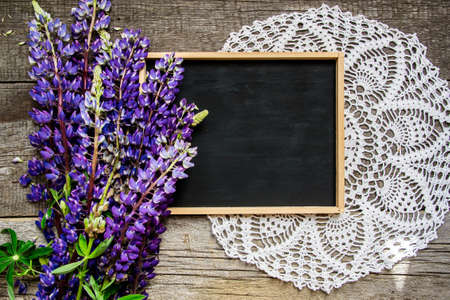 Top view copy space. Black slate board on an old wooden table, lupins and a crocheted napkin.の写真素材