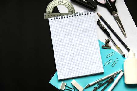 back to school concept. Notepad and school supplies multicolored on a black school board. Top view...