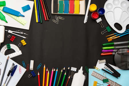 back to school concept. School supplies multicolored on a black school board. Top view with copy space.の写真素材