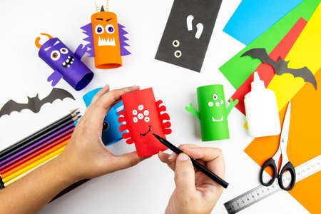 Halloween decoration. DIY and kids creativity concept. Step by step instructions: make a monster from a roll of colored paper toilet paper. Step 9 glue or paint the mouth and eyebrows.の写真素材