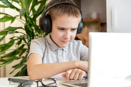 Distance learning online education. A schoolboy is studying at a computer at home and doing school...