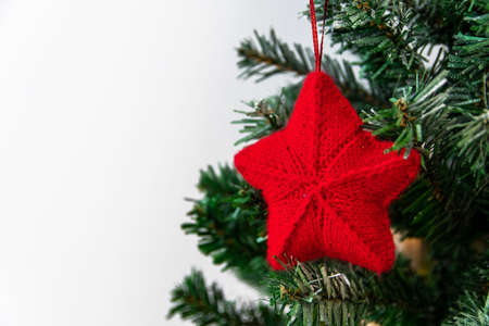 Christmas knitted toy on a Christmas tree red star with a garland on a white background.の写真素材
