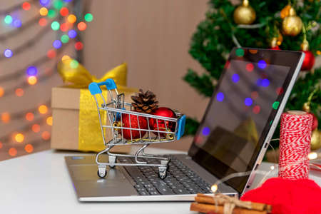 Online shopping concept for Christmas and New Year. Computer and shopping trolley with Christmas balls.の写真素材