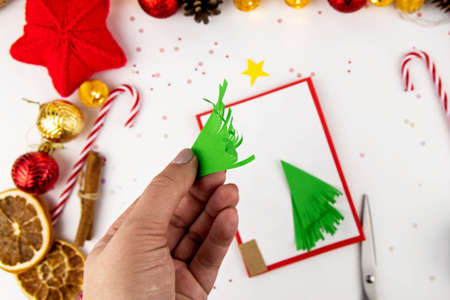 DIY step-by-step instructions for a Christmas card with children. Volumetric tree on a postcard made of colored paper, glue and scissors. Step 3.の写真素材