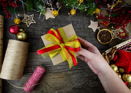 Top view of a female hand holding a Christmas present. Gift wrapping for Christmas.