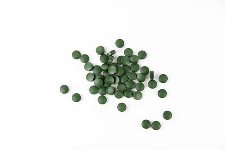Green spirulina pills are scattered on a white background. Copy space.の写真素材