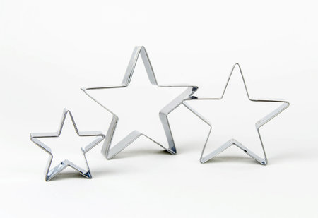 Three metal cookie cutters in the shape of a star of different sizes on a white background. Family concept - mom, dad and child.の写真素材