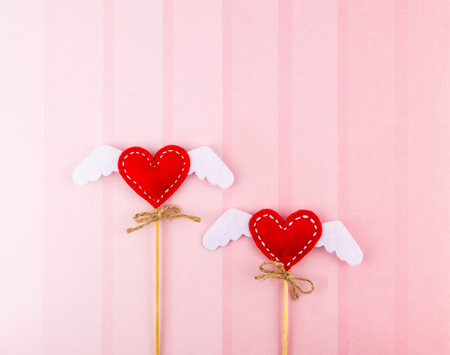 Valentine's Day background. Two hearts with handmade wings on a pink backgroundの写真素材