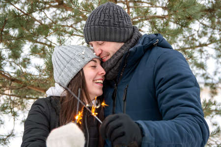 In the winter, a couple in love on the street hold sparklers and rejoiceの写真素材