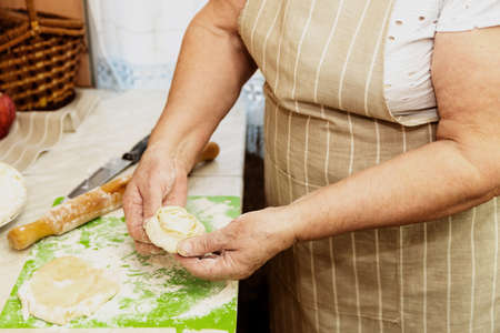 A close-up of an elderly woman's hand with a test. Cooking muffins at home