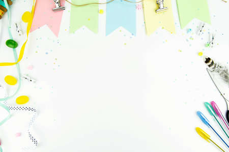 Spring background with free space. View from above on the white background with an ornament of multi-colored paper, ribbons, colored pens, scissors, rulerの写真素材