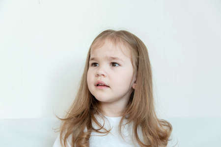Portrait of a girl 3-5 years old with long blond hair in a white T-shirtの写真素材