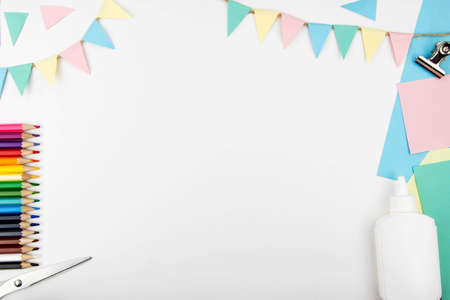 A background with space to copy the concept of creativity and celebration. Colored pencils, colored paper flags, colored paper, glue on a white background view from above.の写真素材