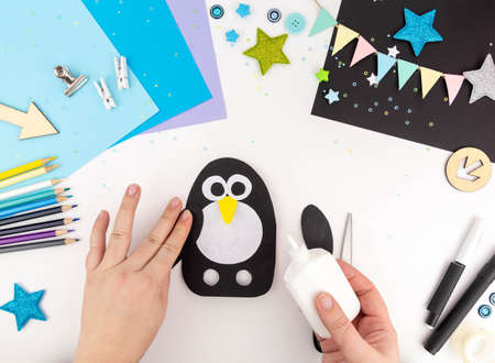 Step-by-step instruction of making a penguin out of paper with children.