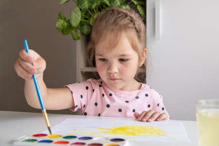 A little girl paints at home. Concept creativityの写真素材