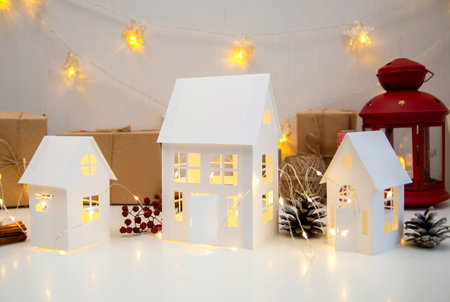 Childrens crafts made of white paper for Christmas, New Year. The decor of the houses is made of cardboard and garlands. Cozy atmosphere.の写真素材