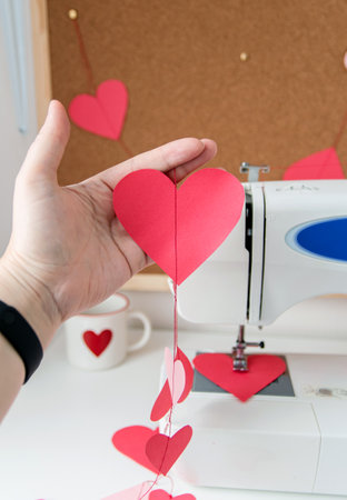 Sewing machine and paper hearts. The process of making a garland. Concept to sew with love,...