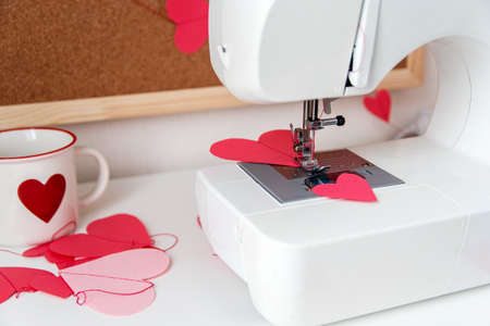Sewing machine and paper hearts. The process of making a garland. Concept to sew with love,...