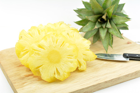 Pineapple on wooden board, The pineapple is a tropical plant with edible multiple fruit consisting of coalesced berries, and the most economically significant plant in the Bromeliaceae family.の写真素材